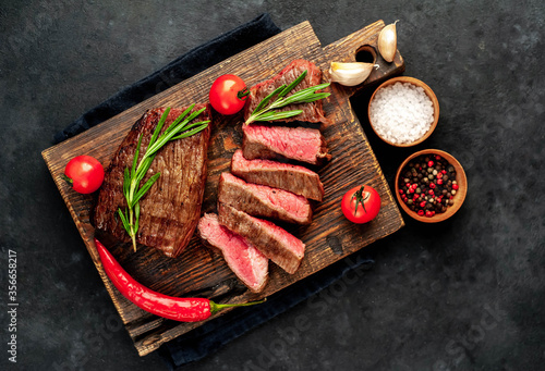  Two grilled beef steaks with spices on a stone background