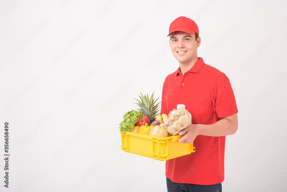 Portrait of a man in red uniform is holding fresh food in plastic box on white background, home delivery concept Portrait of a man in red uniform is holding fresh food in plastic box on white background, home delivery concept