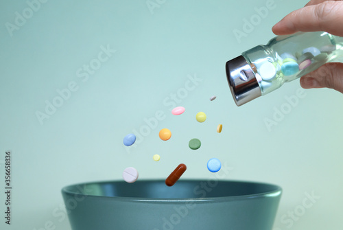 Food additives and microelements. A hand with a salt shaker sprinkles various tablets into a plate, seasoning or replacing food with chemical elements or vitamins instead of spices