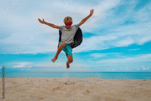 happy boy play superhero on beach vacation