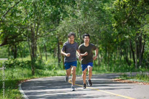 Father and adult son jogging on the park path