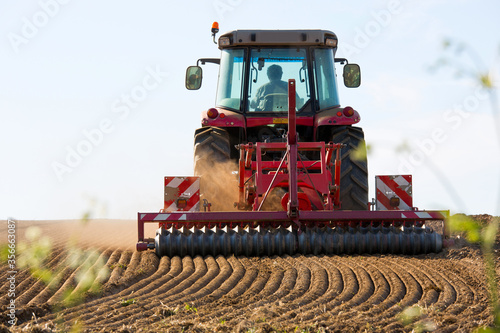 Tracteur labourant la terre en campagne en printemps 