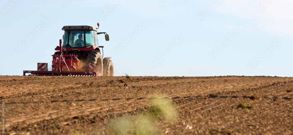 Fototapeta premium Tracteur dans un champ en train de semer du maïs.