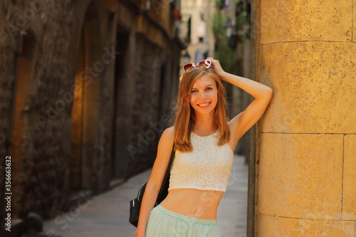 Young smiling woman walking on streets of Barcelona  stone background  noisy shot  sunset time 