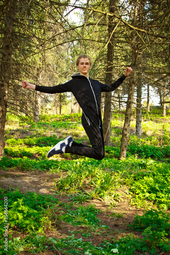 Handsome  young guy in a tracksuit plays sports in the park on the nature. Healthy lifestyle.