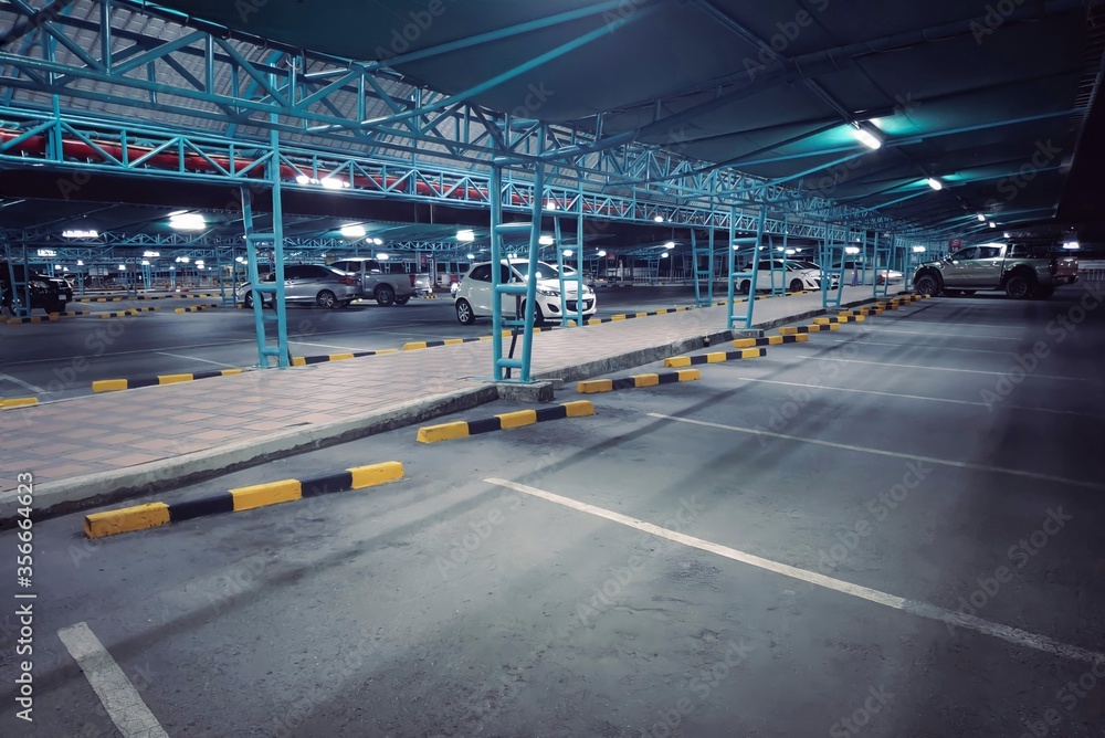 Car parking outdoor area in department store  space available at night.Parking lot with blue roof protects the sunlight and adequate lighting