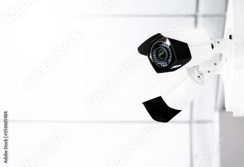 Modern public CCTV cameras on wall with blurred indoor background. Intelligent reccording cameras for monitoring all day and night. Concept of surveillance and monitoring with copy space.