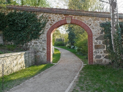 Brick archway in Ochsenzwinger park in Goerlitz. View on path and gate in a warm evening light. Alley in the park located on city walls.