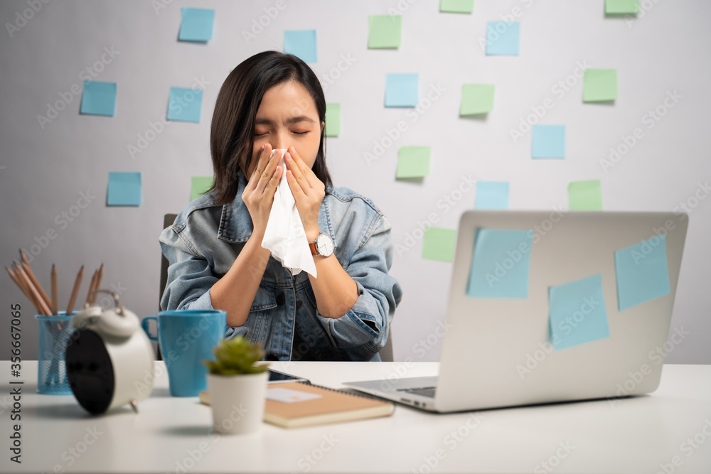 Asian woman working on a laptop was sick with fever sitting at home office. WFH. Work from home. Prevention Coronavirus COVID-19 concept. Asian woman working on a laptop was sick with fever sitting at home office. WFH. Work from home. Prevention Coronavirus COVID-19 concept.