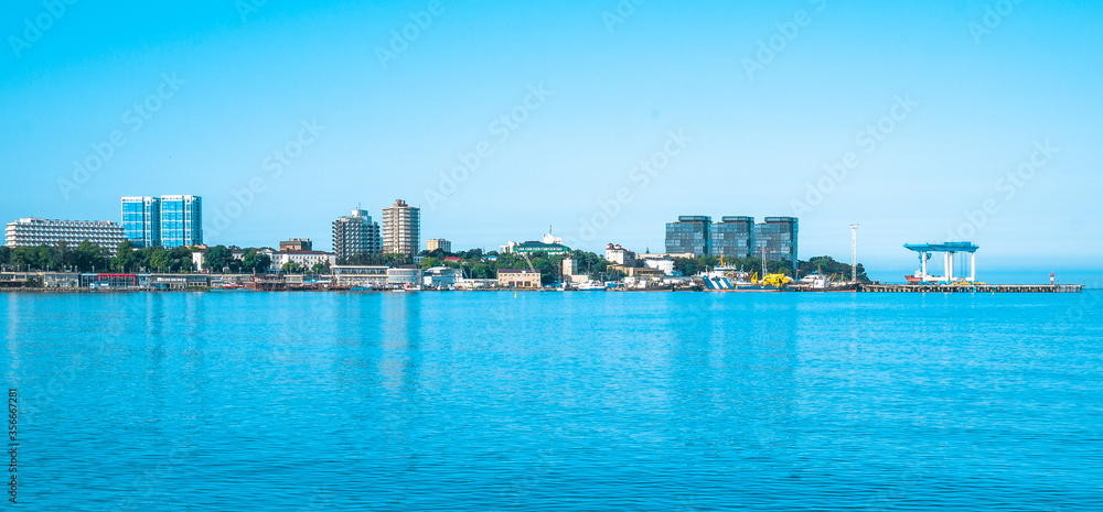 Beautiful city with tall buildings on the shores of the blue sea. Panorama of the coastline with houses on a clear day.