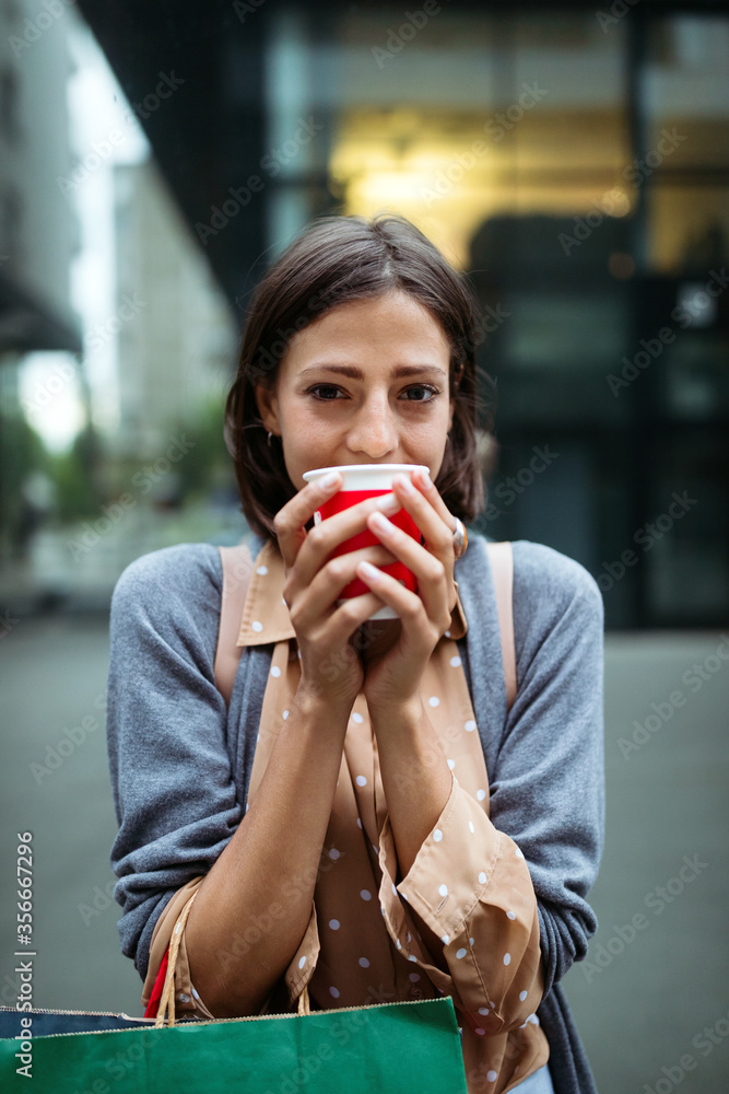 Happy young woman drinking take away coffee and walking with bags after shopping in city. Happy young woman drinking take away coffee and walking with bags after shopping in city.