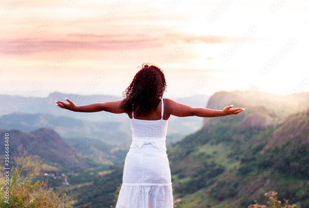 Feeling free. Young black girl with arms raised watching the sunset and feeling happy. Feeling free. Young black girl with arms raised watching the sunset and feeling happy.