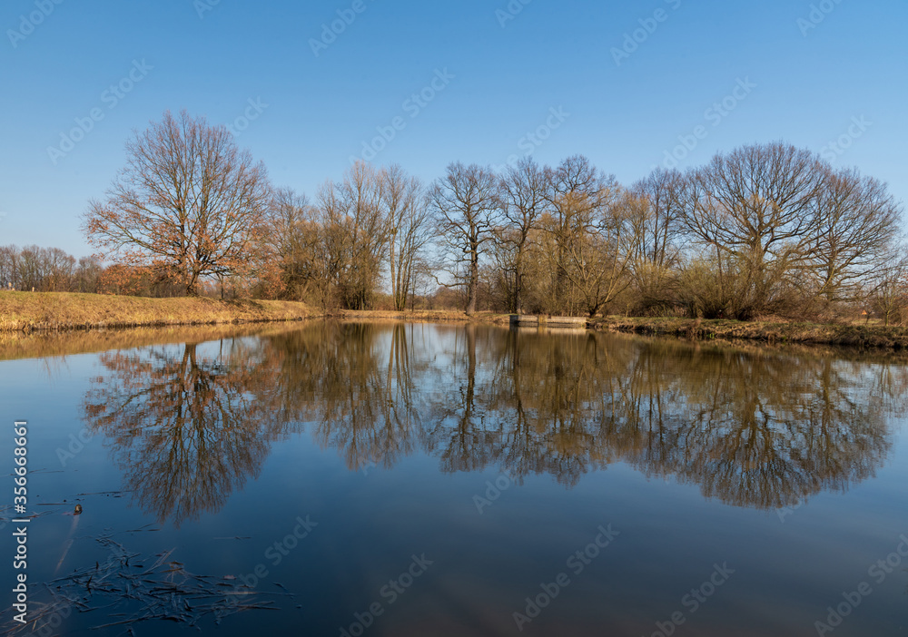 Pond with trees and sky reflection in early spring CHKO Poodri near Ostrava city in Czech republic