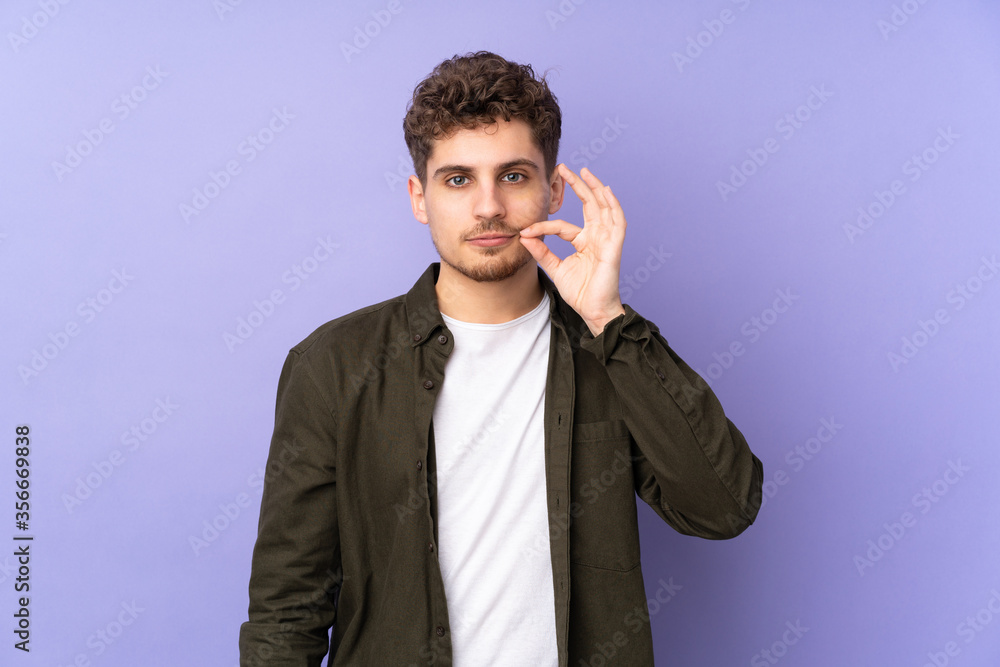 Caucasian man isolated on purple background showing a sign of silence gesture Caucasian man isolated on purple background showing a sign of silence gesture