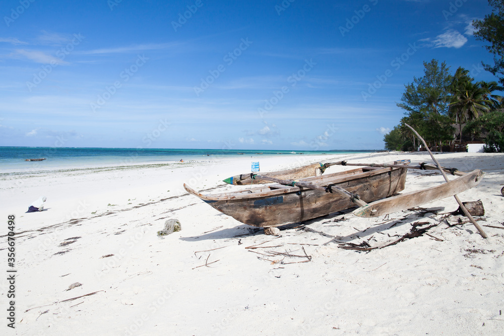 Zanzibar ngalawa boat on a white sand beach during low tide.