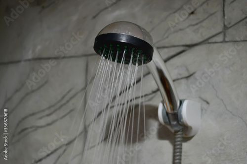 A refreshing shower with water flowing from the shower head and the modern bathroom faucet.