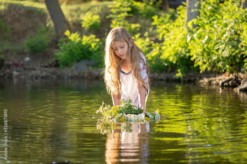 little girl with a wreath in a white dress in the water. Holiday Ivana bathed 