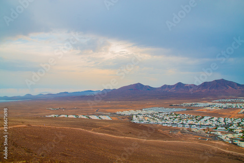  panoramic view of Volcano Montana Roja de Playa Blanca, Lanzarote, Spain. One of the most popular volcano in Canary Islands and the total view of the village in the south with white houses. 
