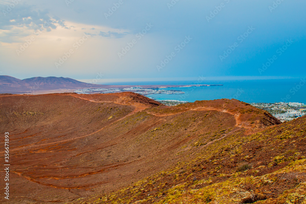  panoramic view of Volcano Montana Roja de Playa Blanca, Lanzarote, Spain. One of the most popular volcano in Canary Islands and the total view of the village in the south with white houses. 
