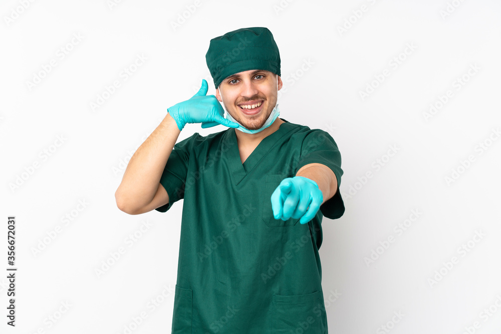 Surgeon in green uniform isolated on isolated white background making phone gesture and pointing front Surgeon in green uniform isolated on isolated white background making phone gesture and pointing front