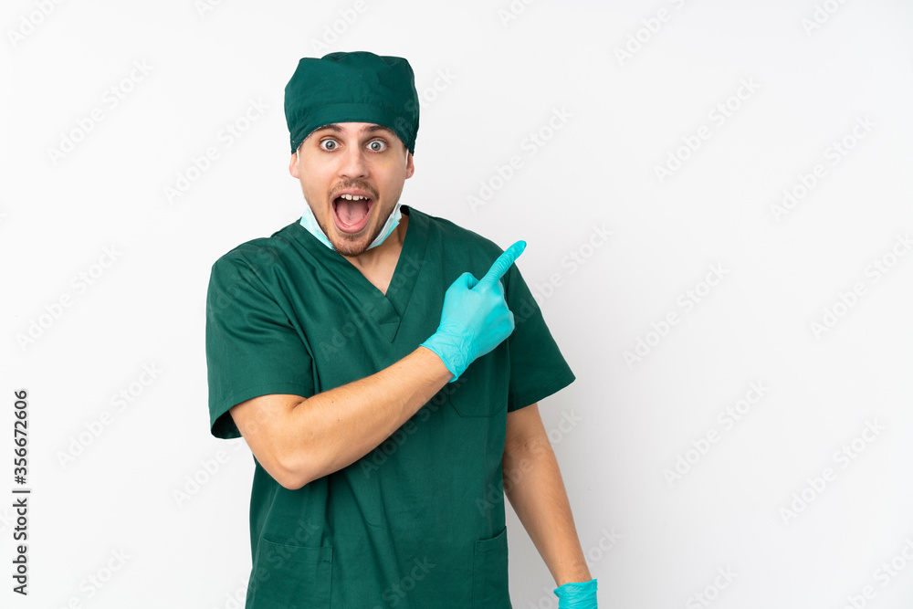 Surgeon in green uniform isolated on isolated white background surprised and pointing side Surgeon in green uniform isolated on isolated white background surprised and pointing side