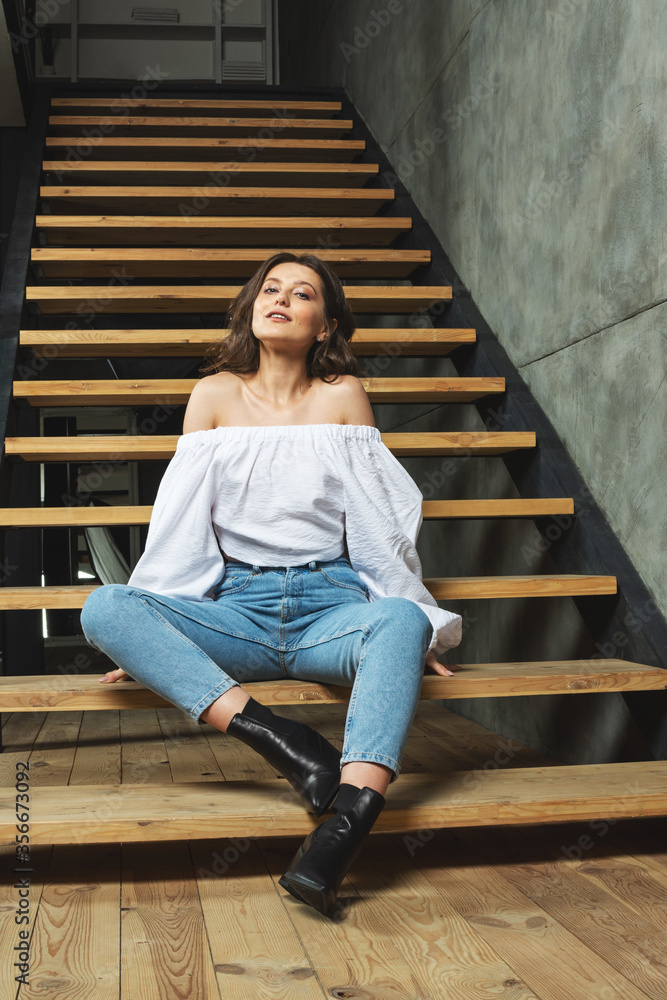 Portrait fashion style woman sit on the stairs inside stylish designe interior room