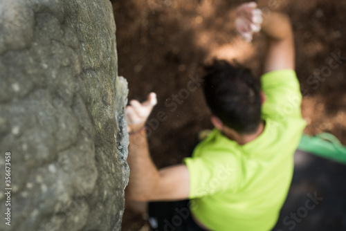 young man falling of a rock wall onto a safety pad/ bouldering pad.