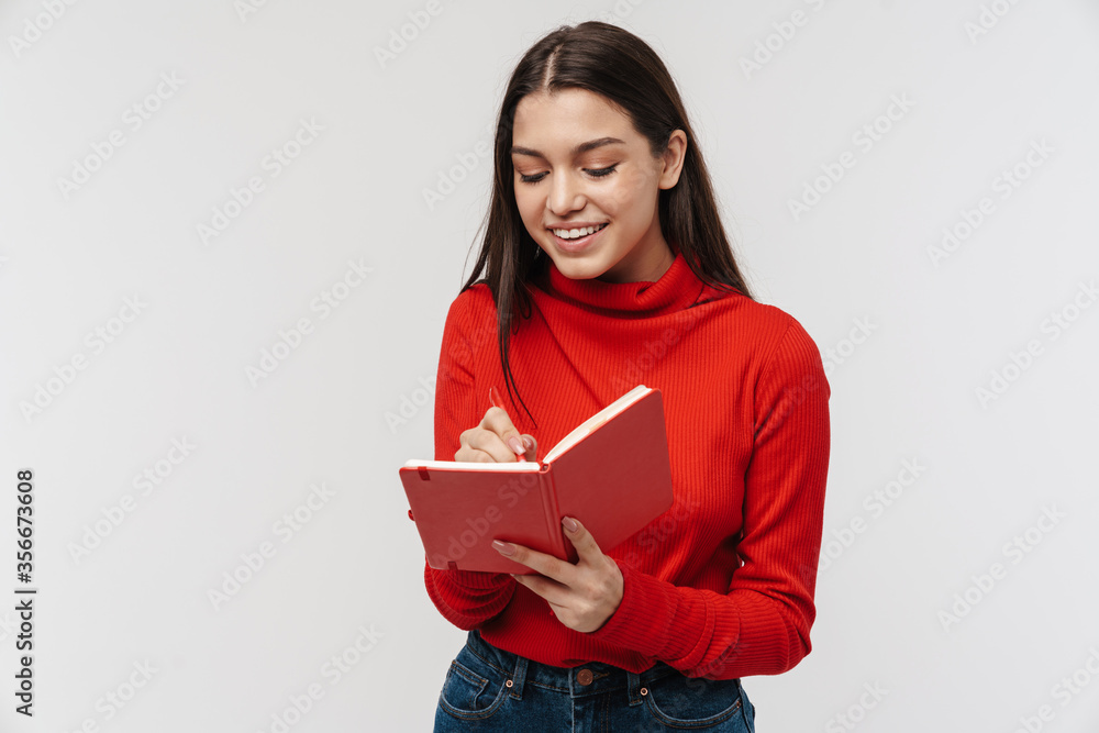 Photo of happy caucasian woman smiling and making notes in planner Photo of happy caucasian woman smiling and making notes in planner