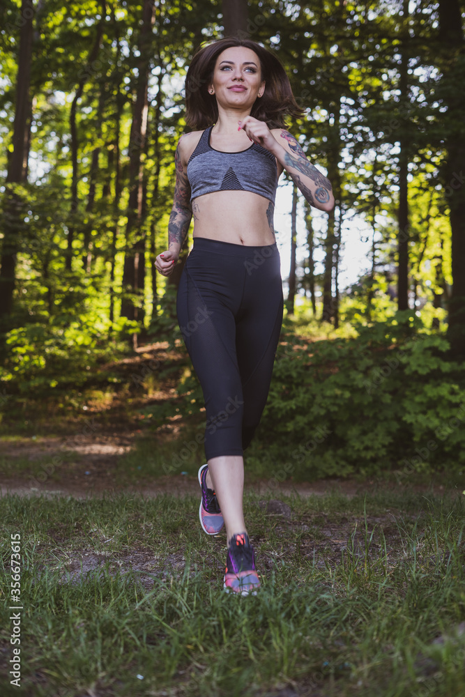 Fototapeta premium wysportowana kobieta wykonuje ćwiczenia na świeżym powietrzu w parku