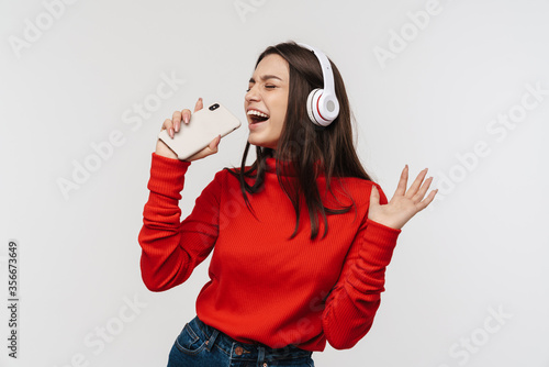 Photo of happy woman singing while using cellphone and headphones photo