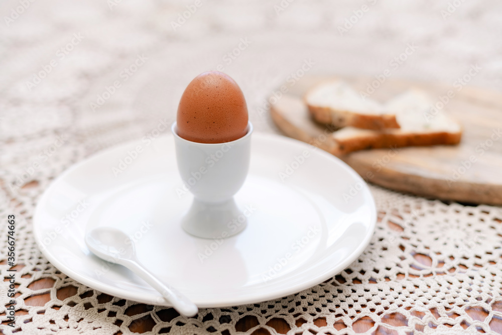 Tasty boiled egg in a cup with crunchy toasted bread for breakfast. Healthy meal on the kitchen table. Tasty boiled egg in a cup with crunchy toasted bread for breakfast. Healthy meal on the kitchen table.