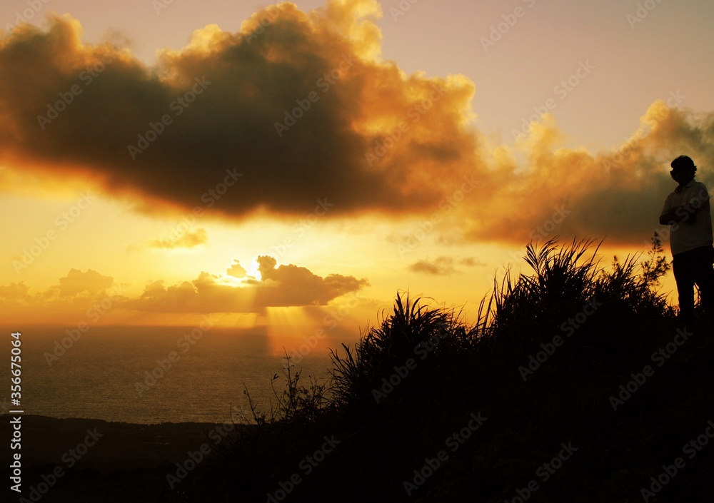 Sunrise at the top of Mt. Tapochao, .View with the silhouette of a man standing on top . Sunrise at the top of Mt. Tapochao, .View with the silhouette of a man standing on top .