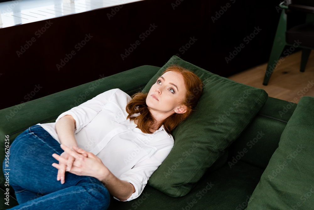 Obraz premium Selective focus of depressed woman with clenched hands lying on couch