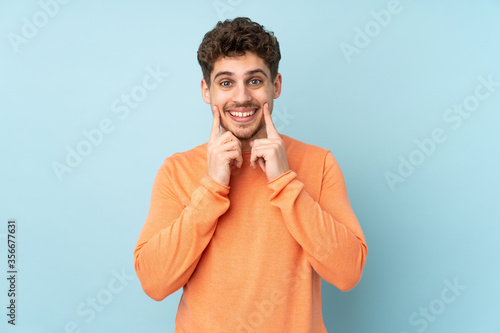 Caucasian man isolated on blue background smiling with a happy and pleasant expression © luismolinero