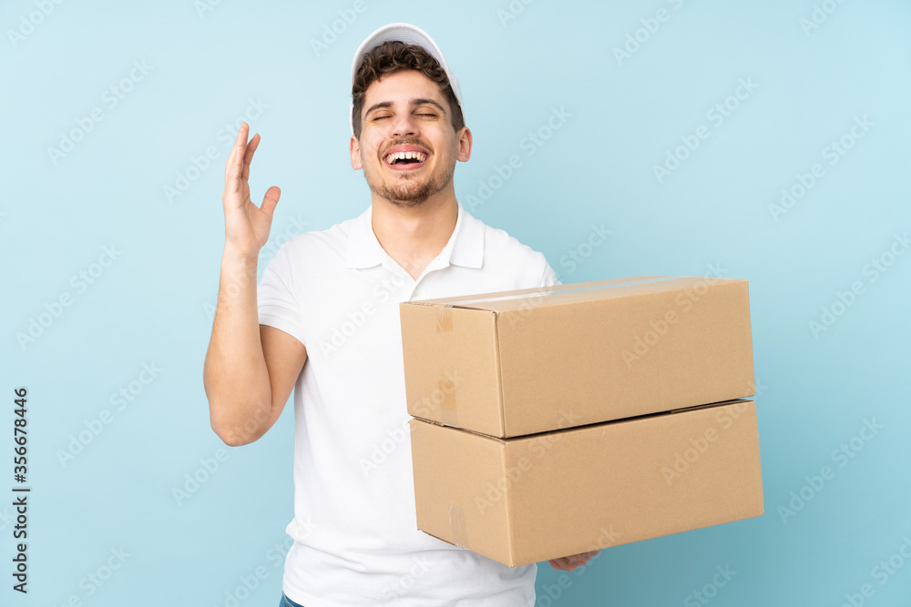 Delivery caucasian man isolated on blue background laughing Delivery caucasian man isolated on blue background laughing