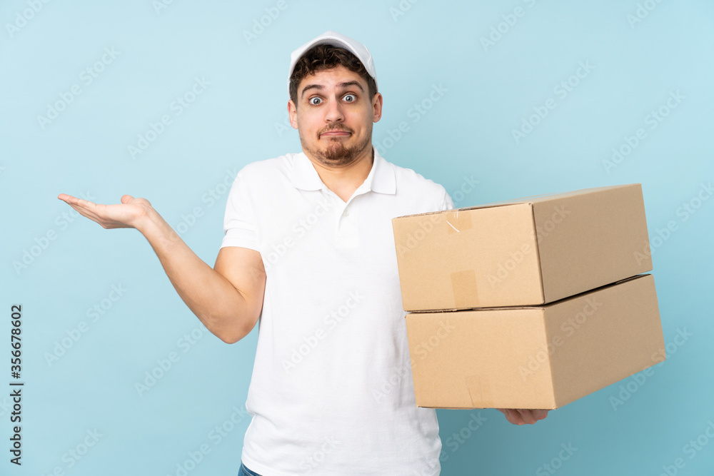 Delivery caucasian man isolated on blue background having doubts with confuse face expression Delivery caucasian man isolated on blue background having doubts with confuse face expression