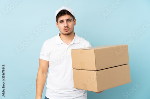 Delivery caucasian man isolated on blue background sad