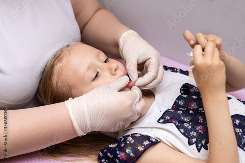 Little girl in class with a speech therapist . The use of special tools for speech correction.
