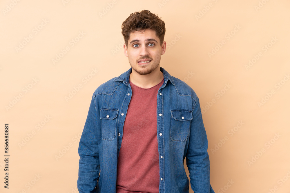 Fototapeta premium Caucasian man isolated on beige background having doubts and with confuse face expression