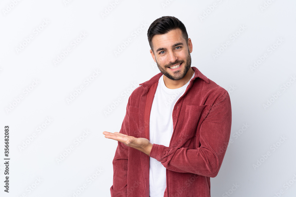 Young handsome man with beard wearing a corduroy jacket over isolated white background presenting an idea while looking smiling towards Young handsome man with beard wearing a corduroy jacket over isolated white background presenting an idea while looking smiling towards