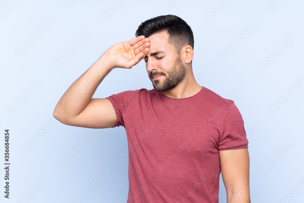 Young handsome man with beard over isolated blue background with tired and sick expression Young handsome man with beard over isolated blue background with tired and sick expression