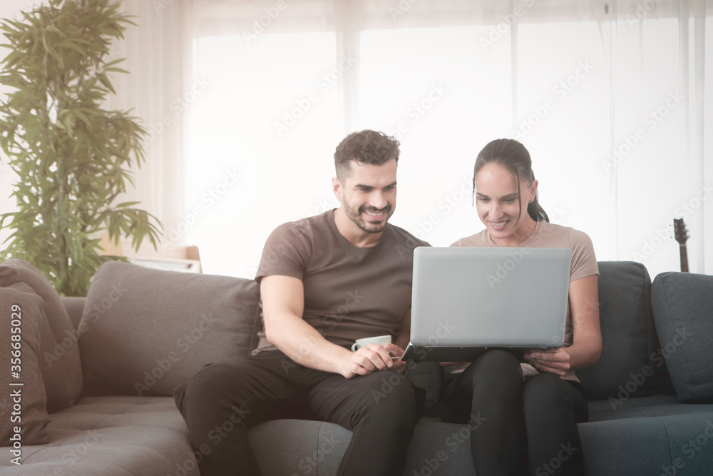 Couple working on laptop computer at home, searching online information and shopping, young people using social media for business online meeting at living room, new normal work form home concept Couple working on laptop computer at home, searching online information and shopping, young people using social media for business online meeting at living room, new normal work form home concept