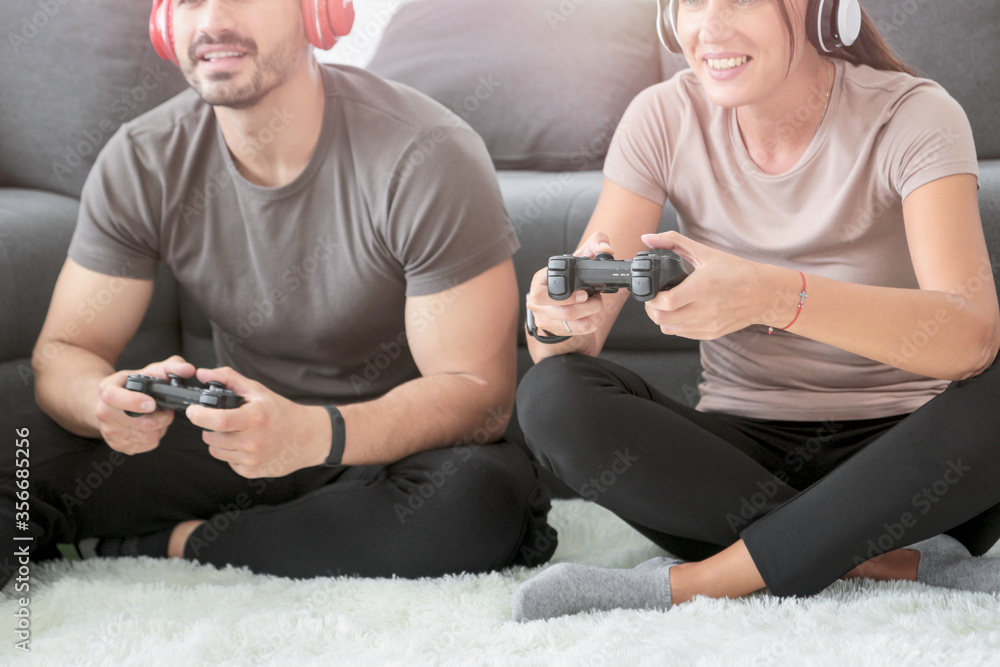 Foto de Happy joyful couple having fun playing video-game at home ...