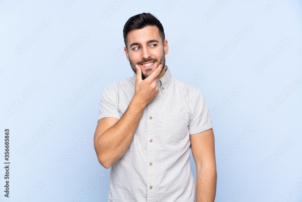 Young handsome man with beard over isolated blue background thinking an idea Young handsome man with beard over isolated blue background thinking an idea