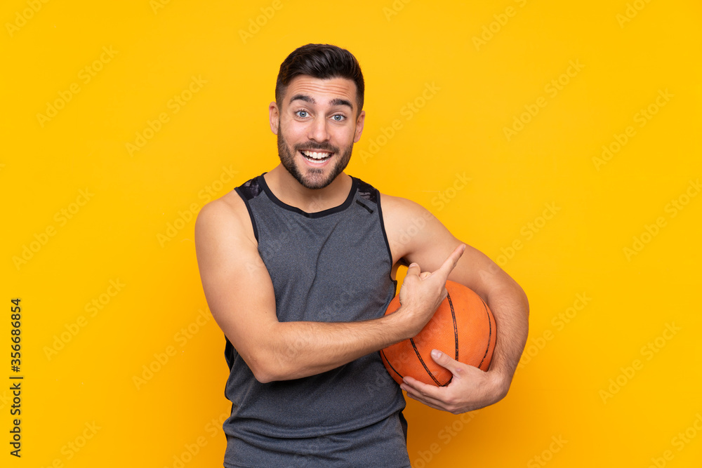 Handsome young basketball player man over isolated white wall pointing to the side to present a product Handsome young basketball player man over isolated white wall pointing to the side to present a product