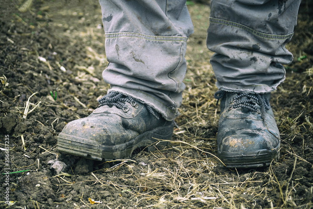 Worker's feet in dusty boots. A man in overalls and work boots. Work clothes