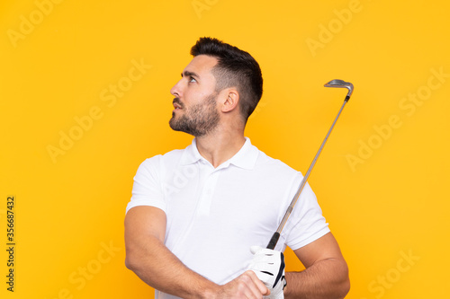 Man over isolated yellow background playing golf