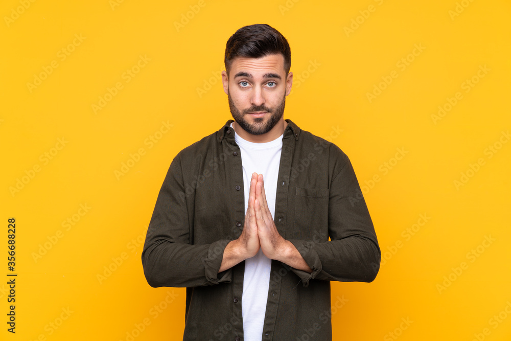 Man over isolated yellow background pleading Man over isolated yellow background pleading