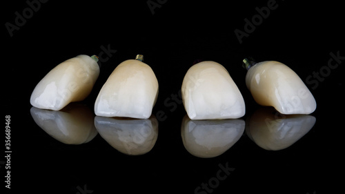 view of the cutting edges of the four dental crowns of the central incisors on a black background with reflection
