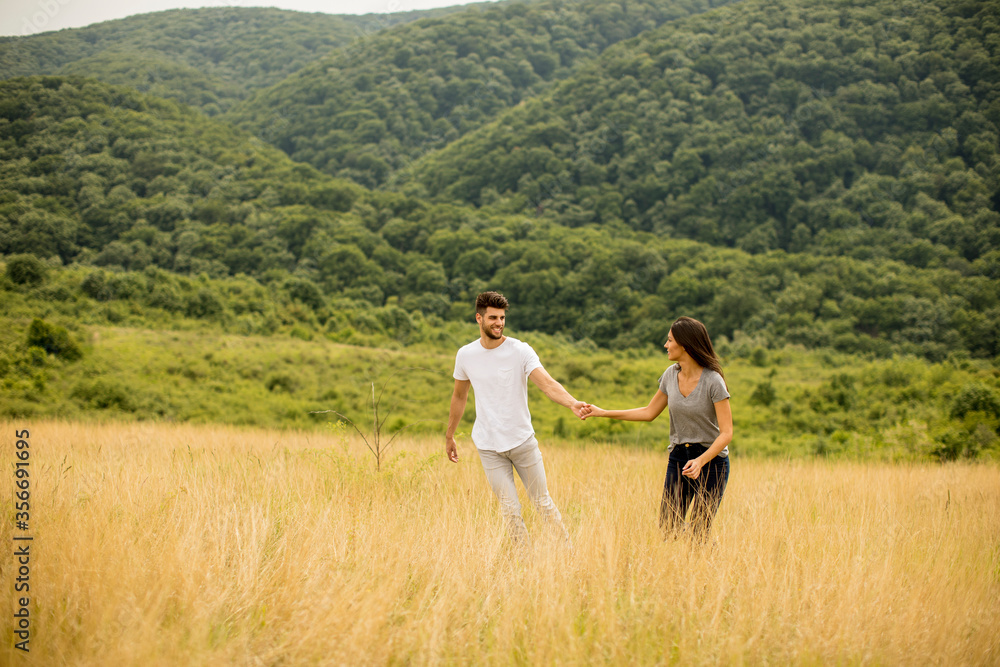 Happy young couple in love walking through grass field